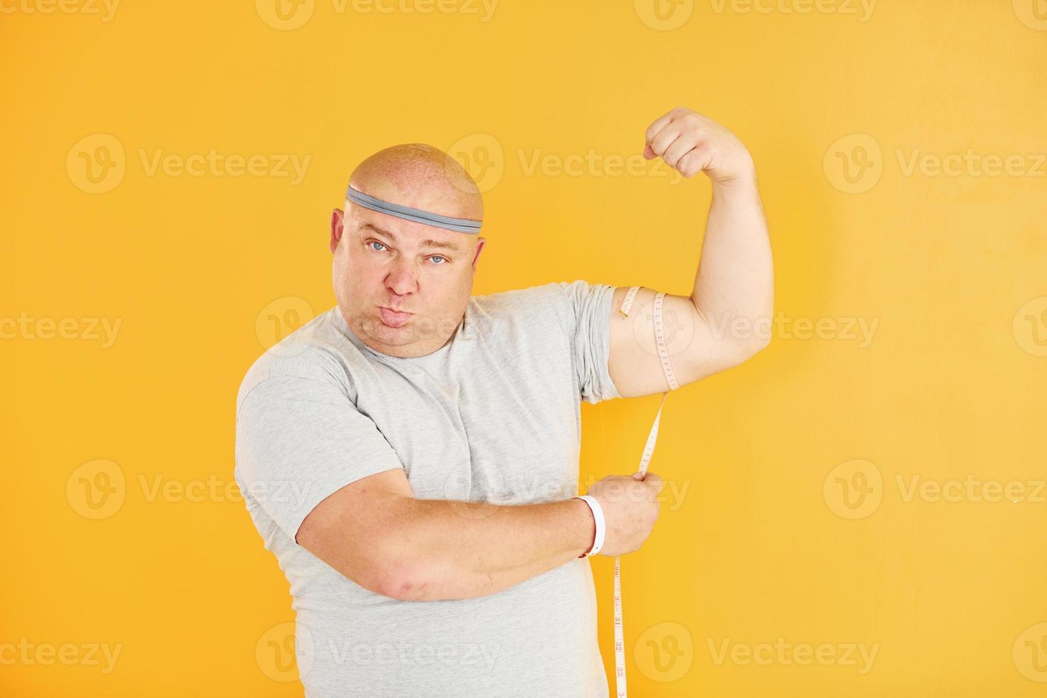 grappig te zwaar Mens in sportief hoofd stropdas is tegen geel achtergrond foto