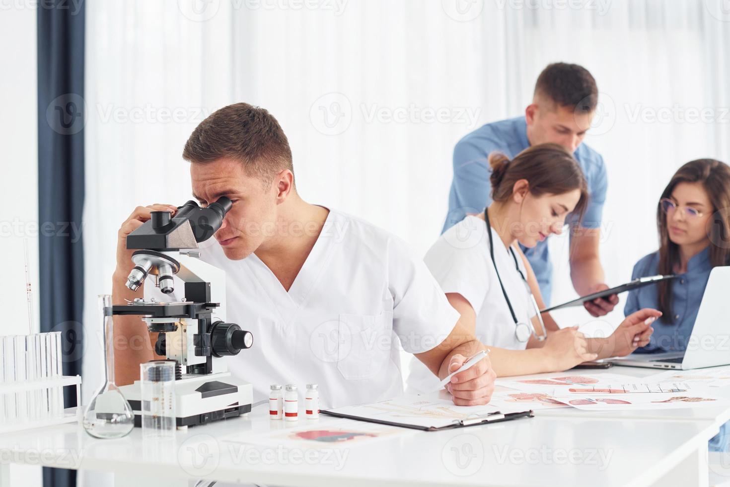 Mens met microscoop. groep van jong artsen is werken samen in de modern kantoor foto