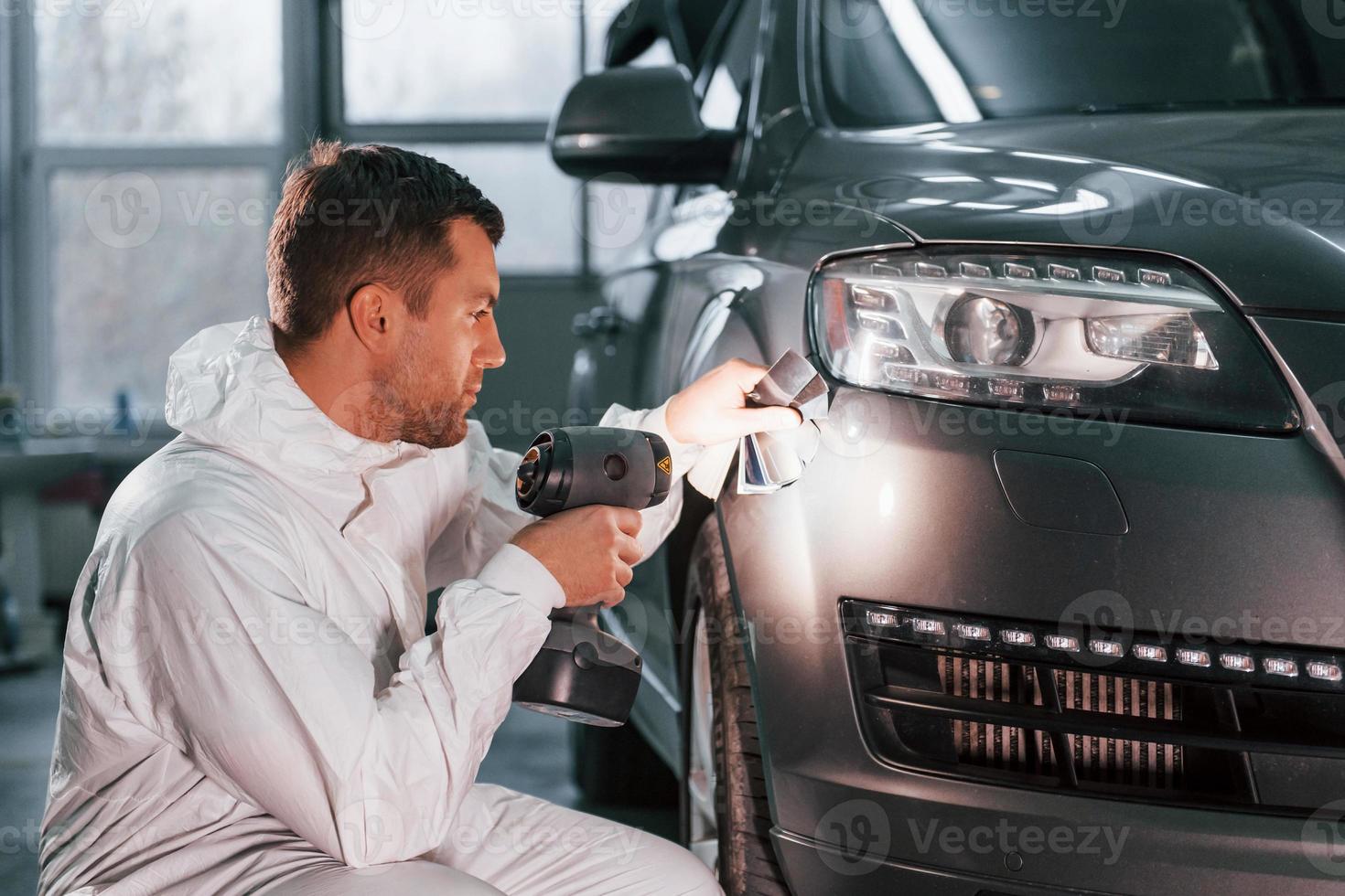 gebruik makend van speciaal apparatuur. Mens in uniform is werken in de auto onderhoud foto