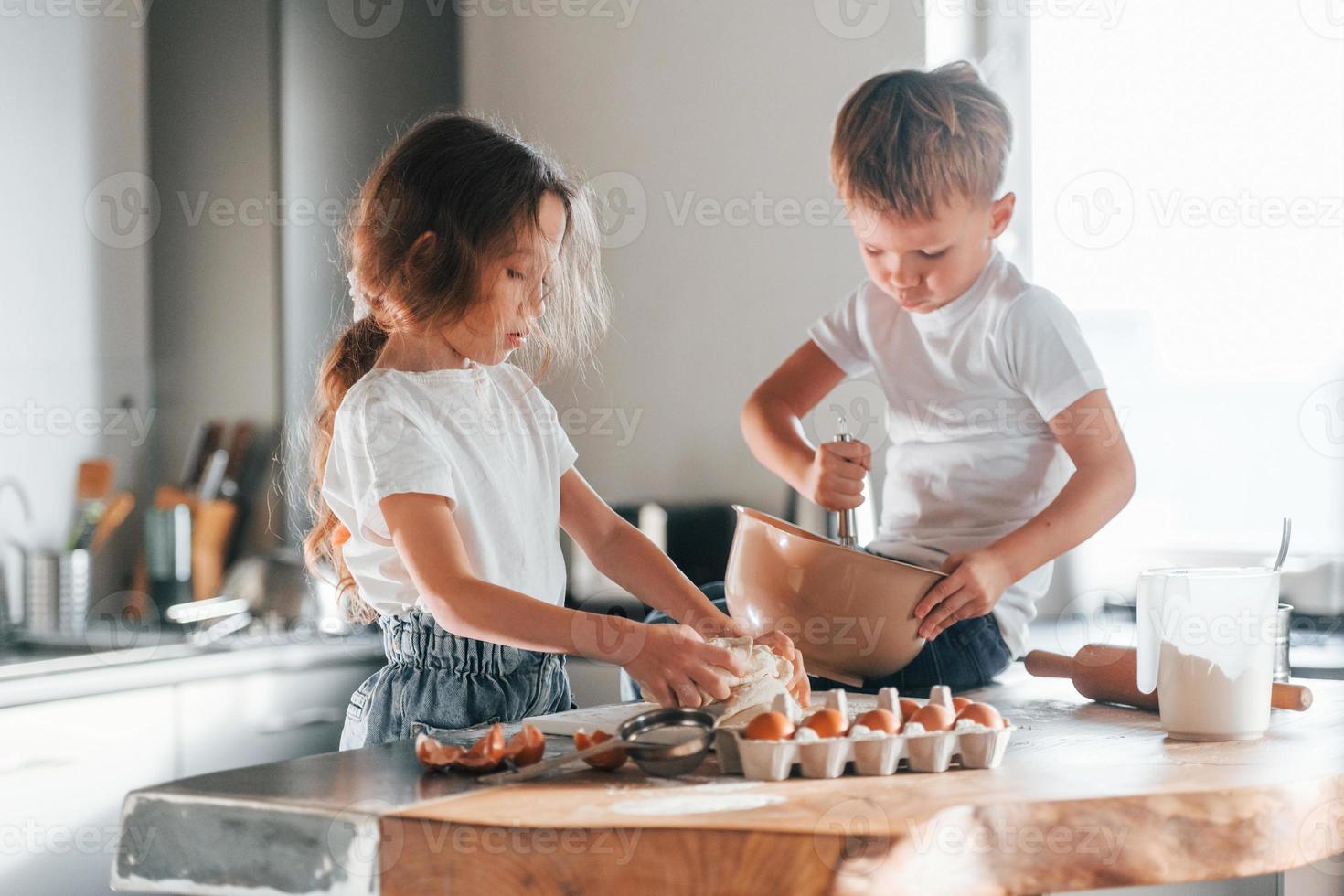 zittend Aan de tafel. weinig jongen en meisje voorbereidingen treffen Kerstmis koekjes Aan de keuken foto