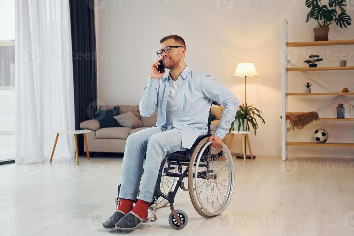 gebruik makend van telefoon. gehandicapt Mens in rolstoel is Bij huis foto