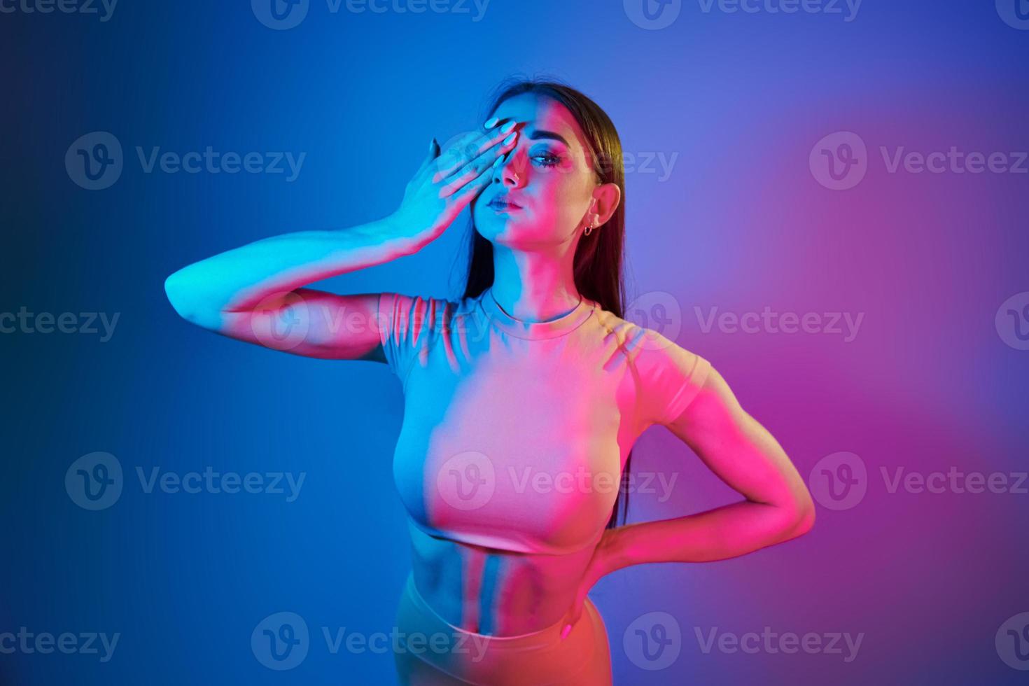 slank lichaam. modieus jong vrouw staand in de studio met neon licht foto