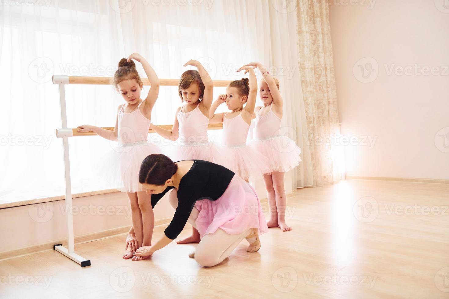 werken met coach. weinig ballerina's voorbereidingen treffen voor prestatie door beoefenen dans beweegt foto