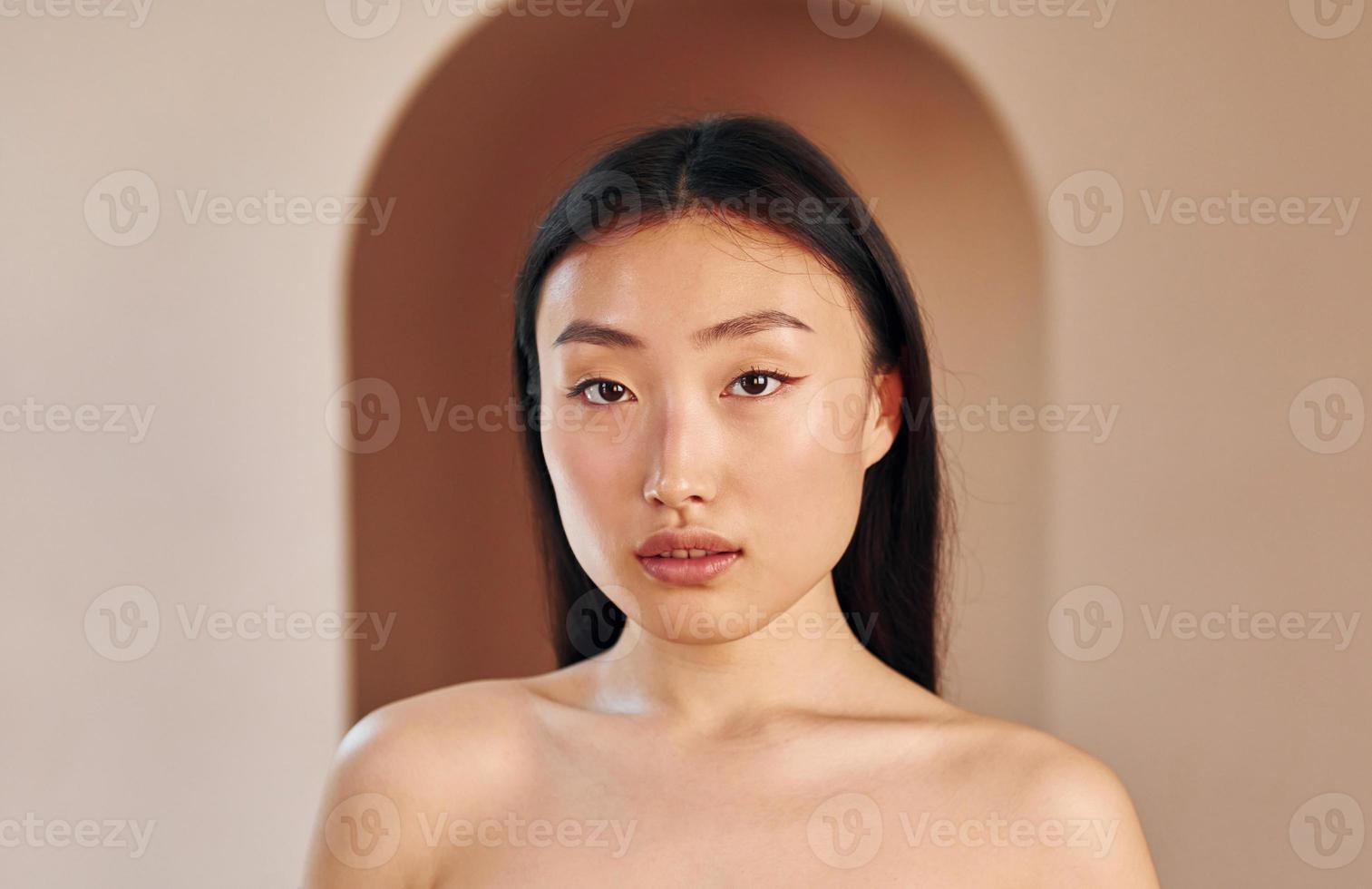 jong echt Aziatisch vrouw staand binnenshuis foto
