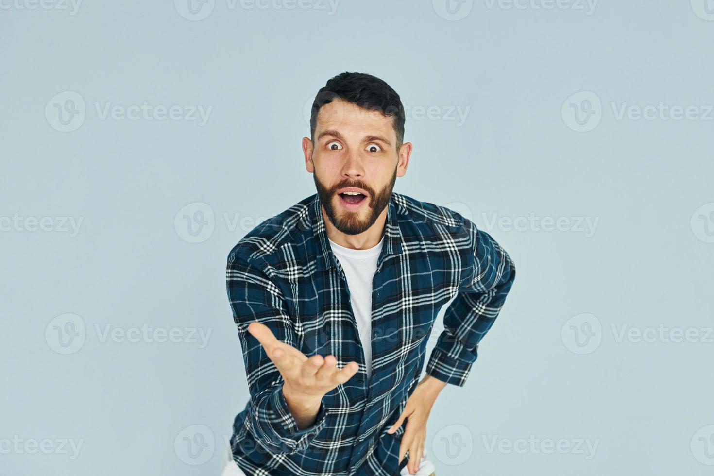 in in een plaid shirt. jong Mens in gewoontjes kleren staand binnenshuis in de studio foto