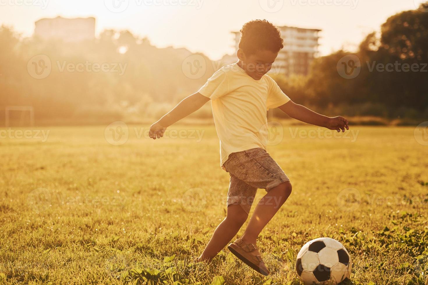 Toneelstukken voetbal. Afrikaanse Amerikaans kind hebben pret in de veld- Bij zomer dag foto