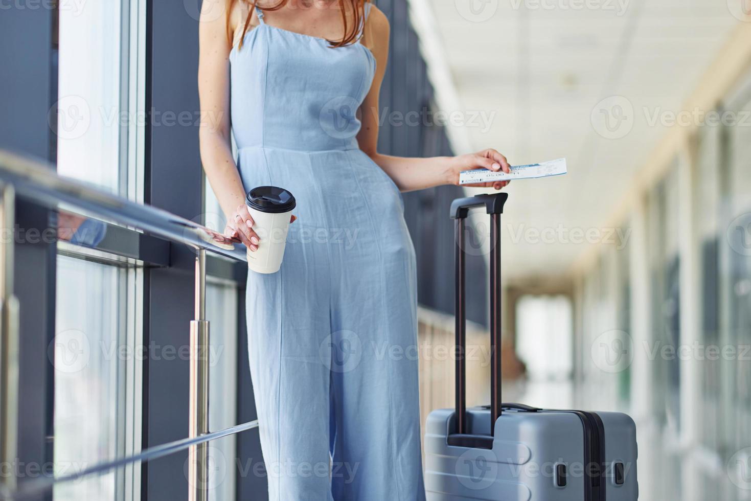 vrouw met ticket. jong reiziger is Aan de Ingang hal in de luchthaven foto