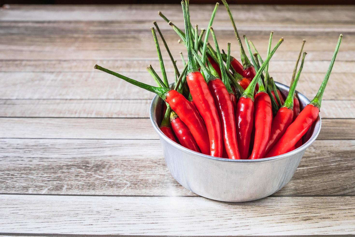 rode chili in een kom op een houten tafel foto