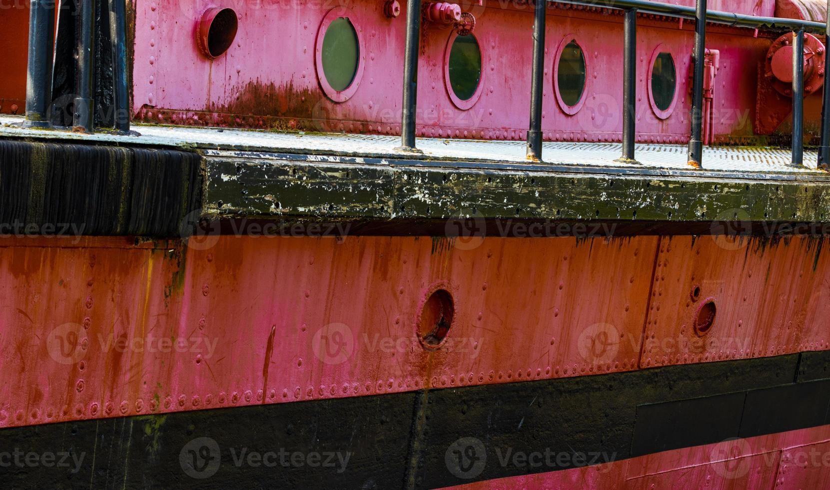 patrijspoorten en dek Aan een oud rood roestig boot foto
