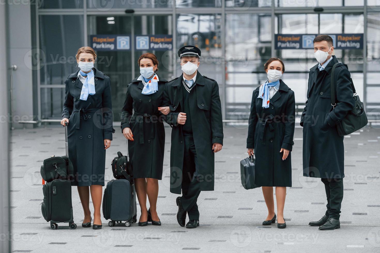 vliegtuig bemanning in werk uniform is samen buitenshuis in de luchthaven foto