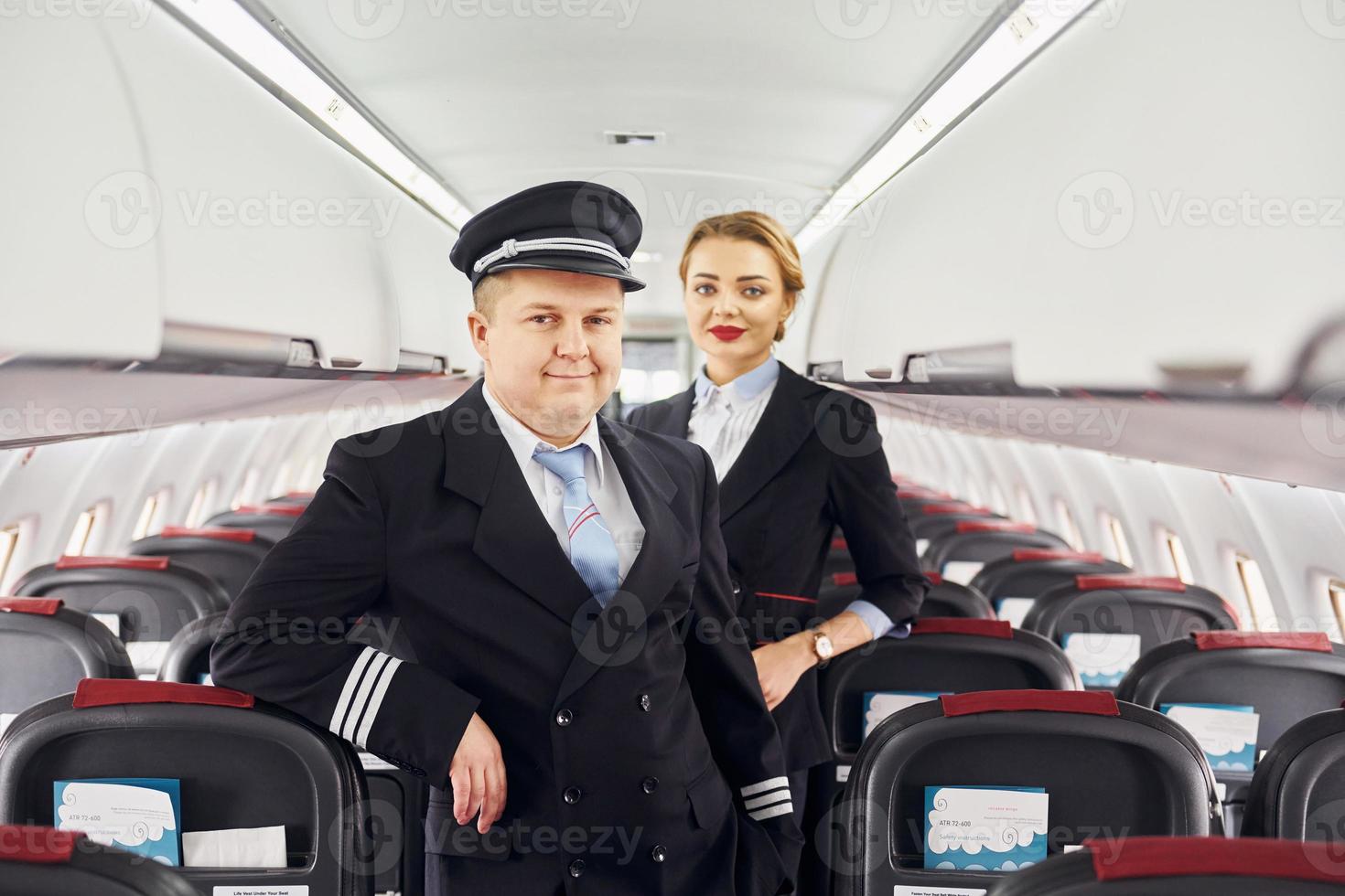 piloot in uniform en stewardess is staand binnen van vliegtuig foto