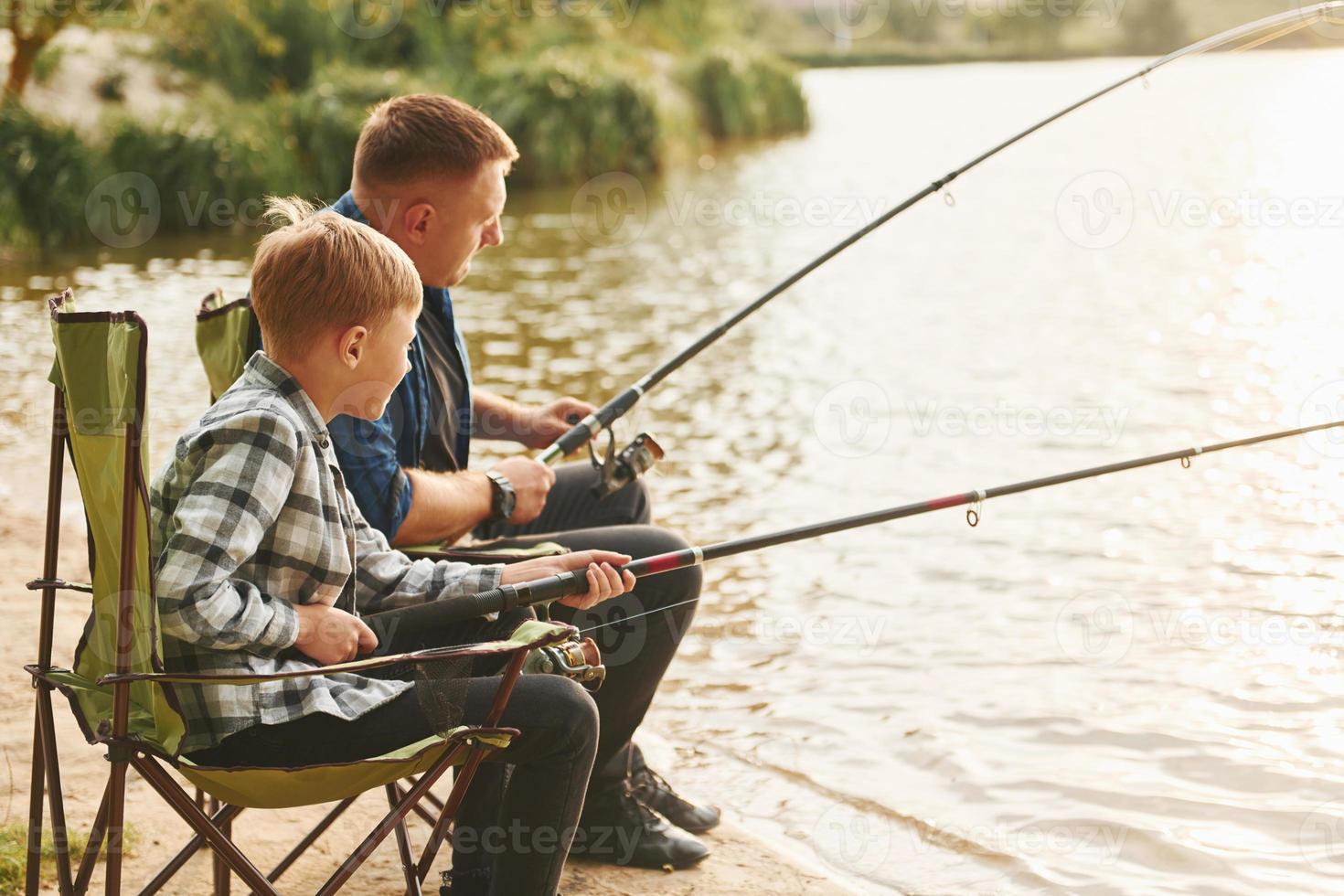 resting en hebben plezier. vader en zoon Aan visvangst samen buitenshuis Bij zomertijd foto