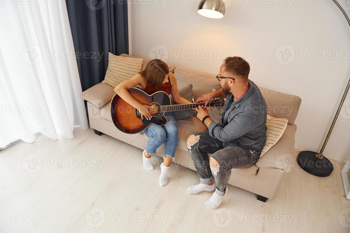 privaat les. gitaar leraar tonen hoe naar Speel de instrument naar jong vrouw foto