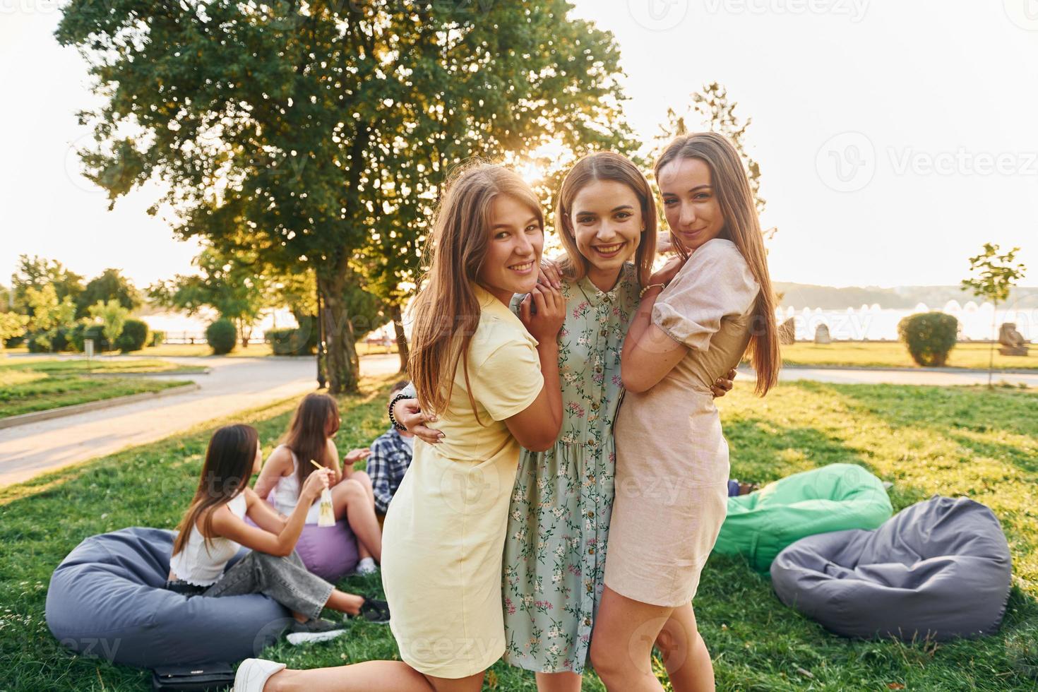 Dames omarmen elk ander. groep van jong mensen hebben een partij in de park Bij zomer dag foto