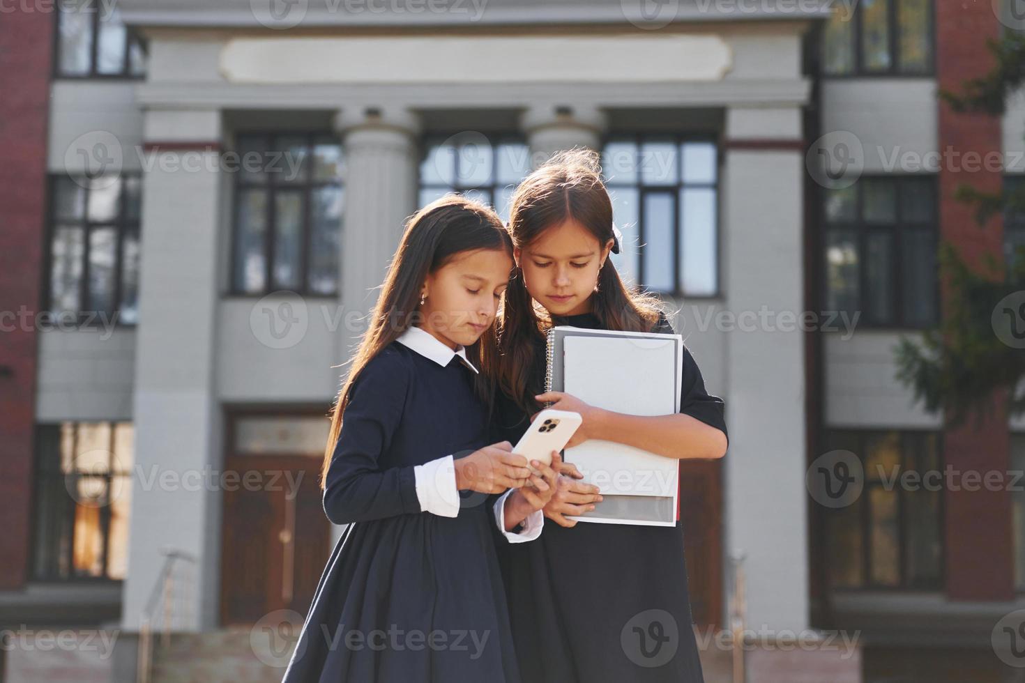 voorkant visie. twee schoolmeisjes is buiten samen in de buurt school- gebouw foto