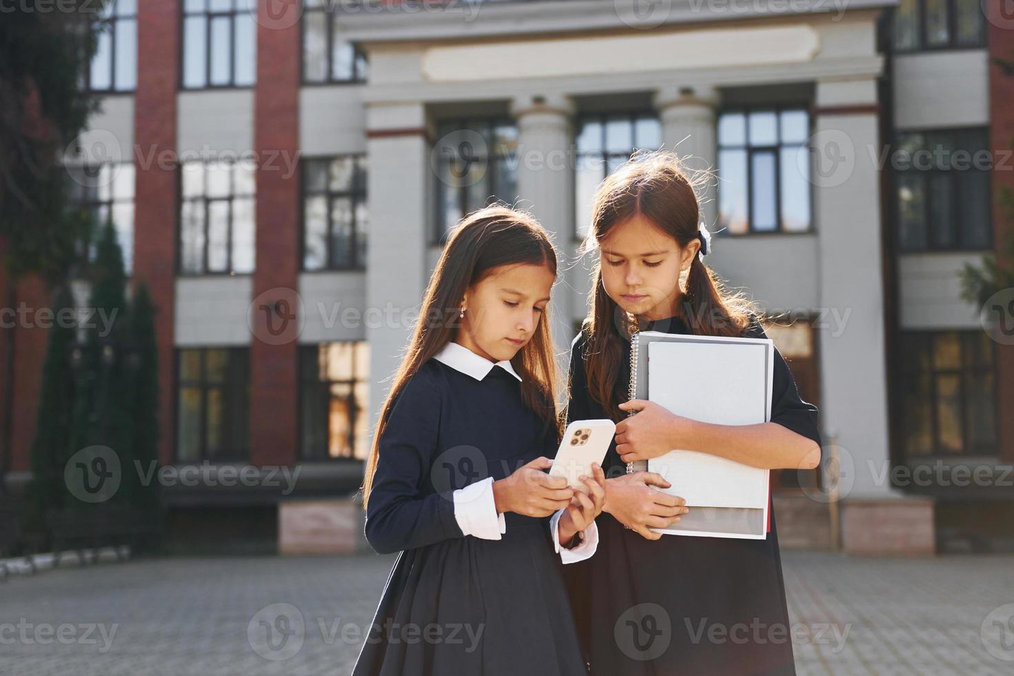 voorkant visie. twee schoolmeisjes is buiten samen in de buurt school- gebouw foto