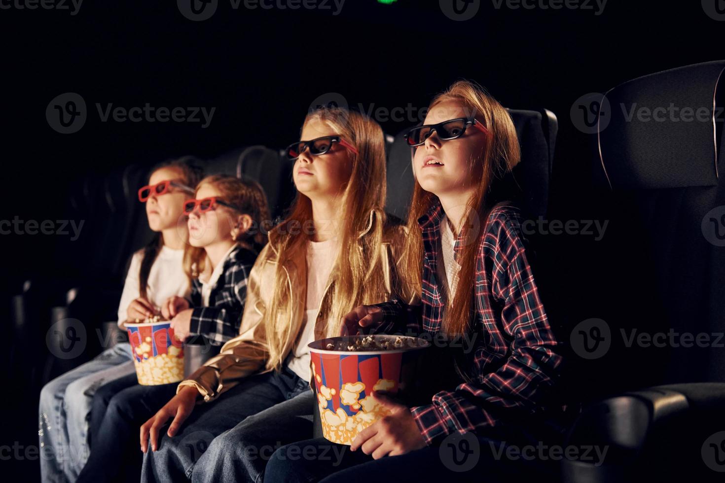 gelaats uitdrukkingen. groep van kinderen zittend in bioscoop en aan het kijken film samen foto