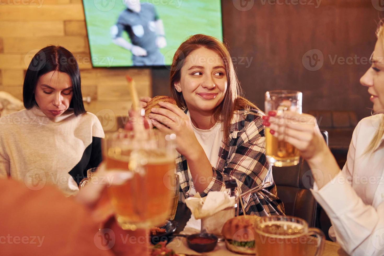 pratend met elk ander. groep van jong vrienden zittend samen in bar met bier foto