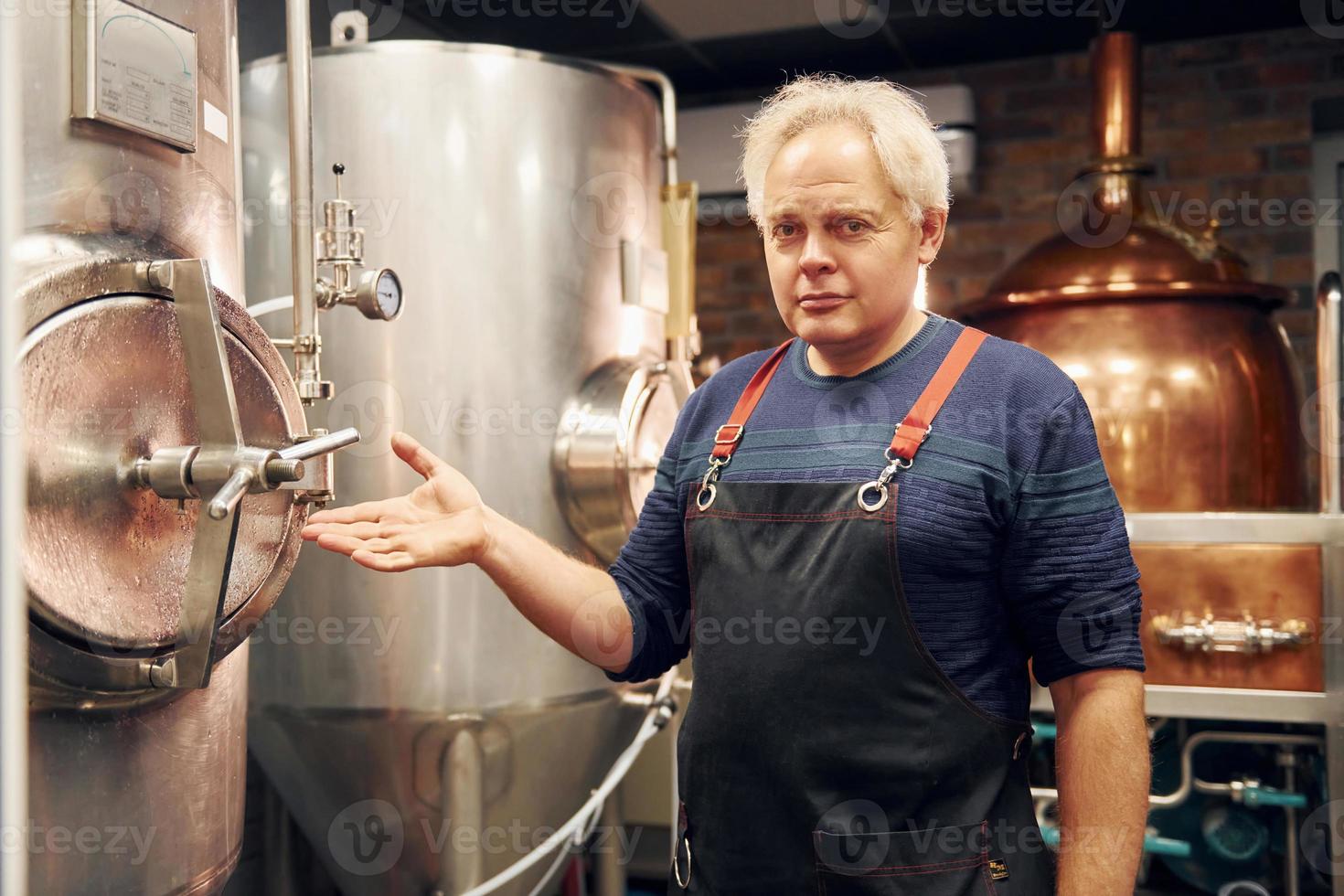 senior Mens is staand in de opslagruimte met uitrusting voor bier foto