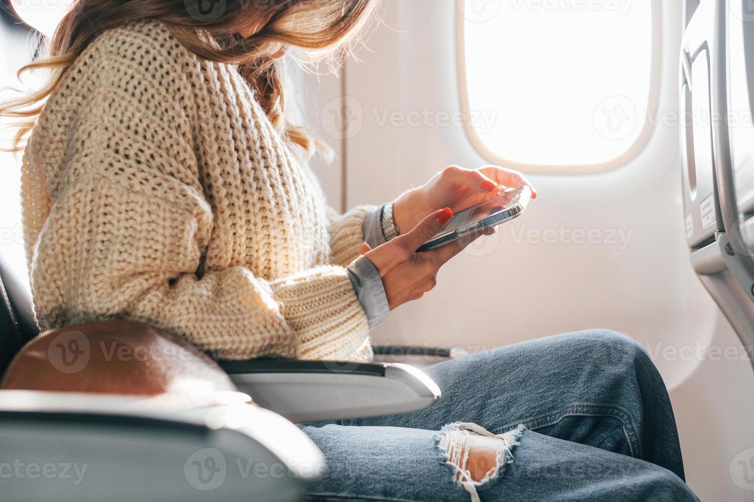 zittend met telefoon in handen. jong vrouw passagier in gewoontjes kleren is in de vlak foto