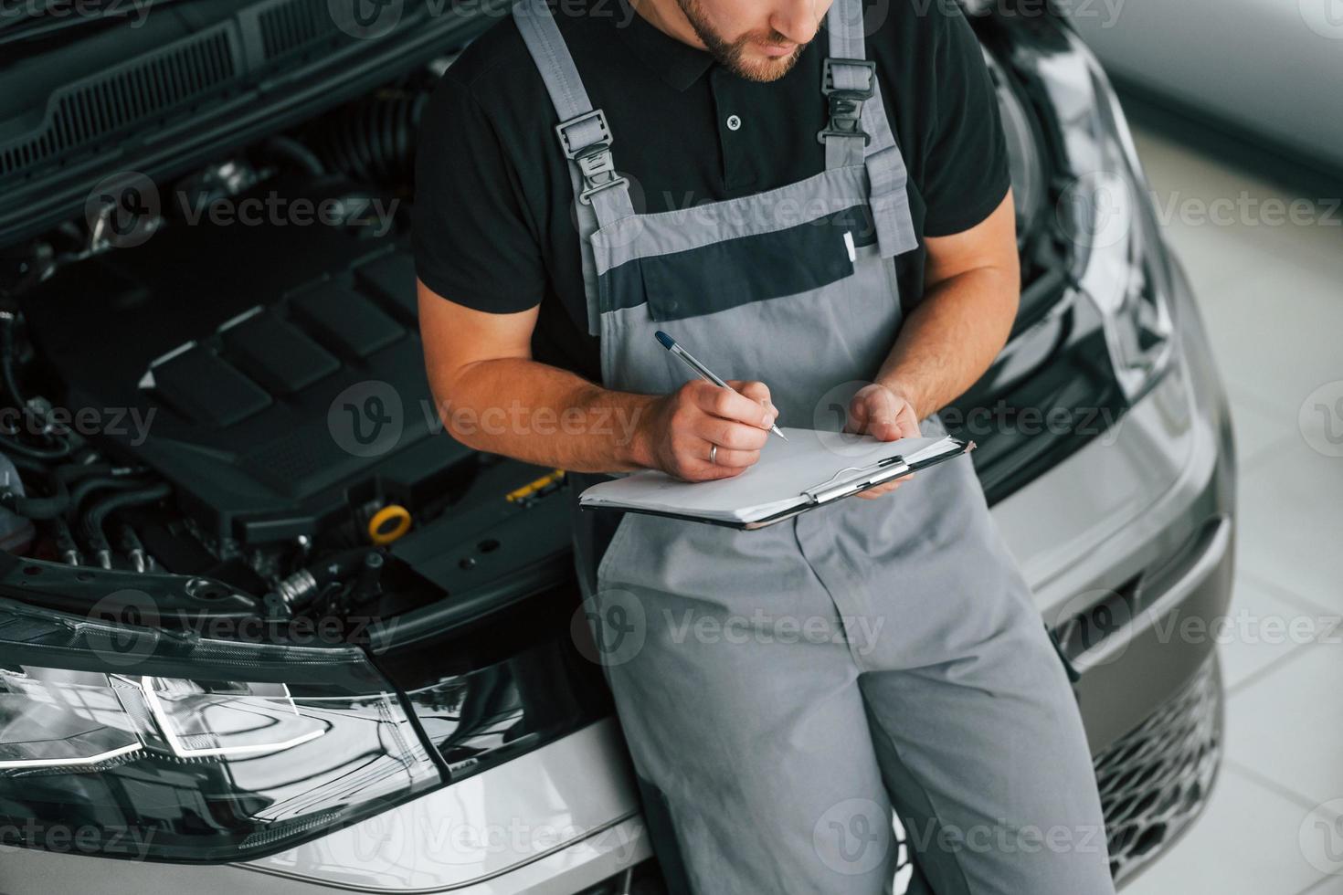 in de buurt de auto. Mens in uniform is werken in de autosalon Bij dag foto