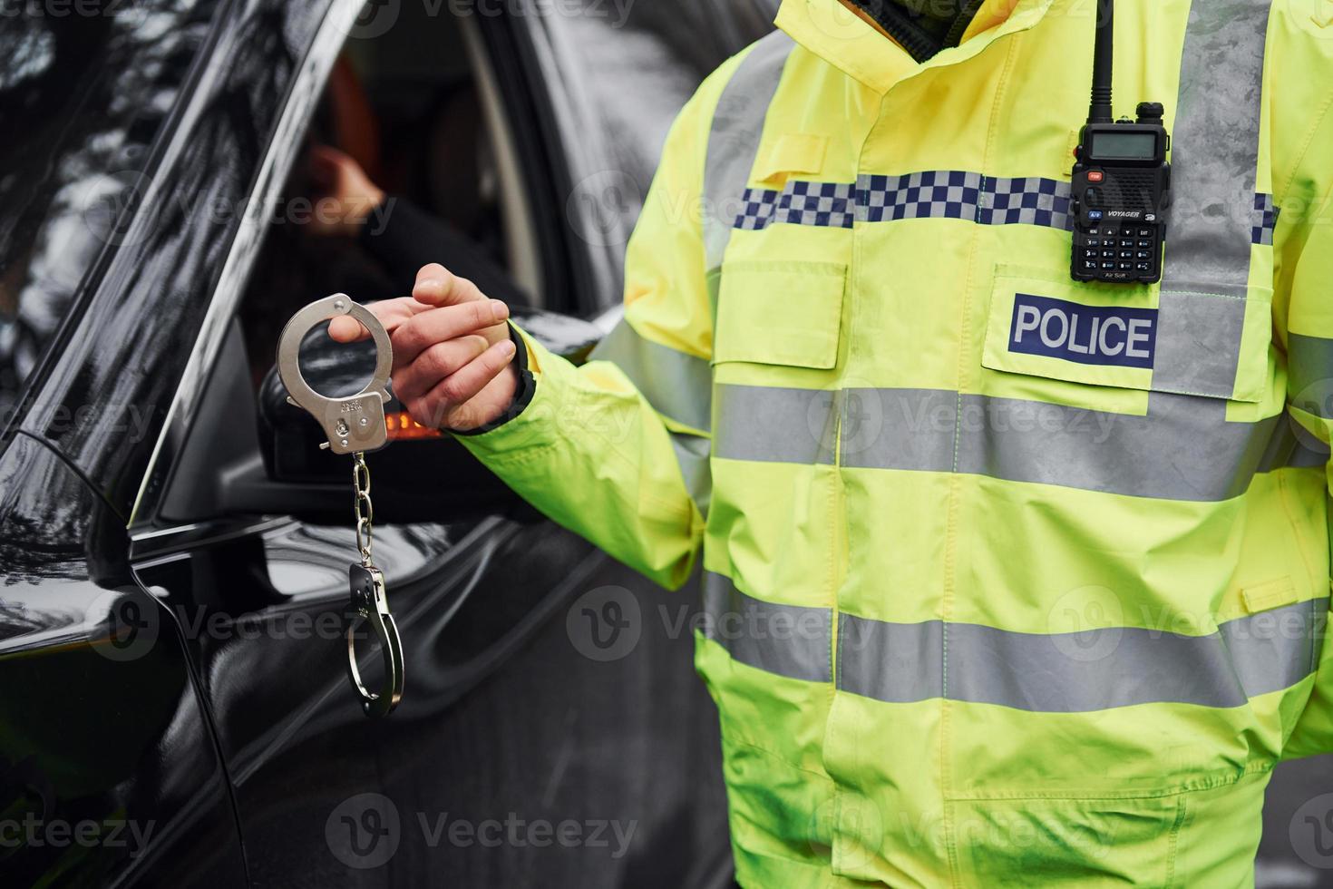 mannetje Politie officier in groen uniformstaand met handboeien in de buurt auto- foto