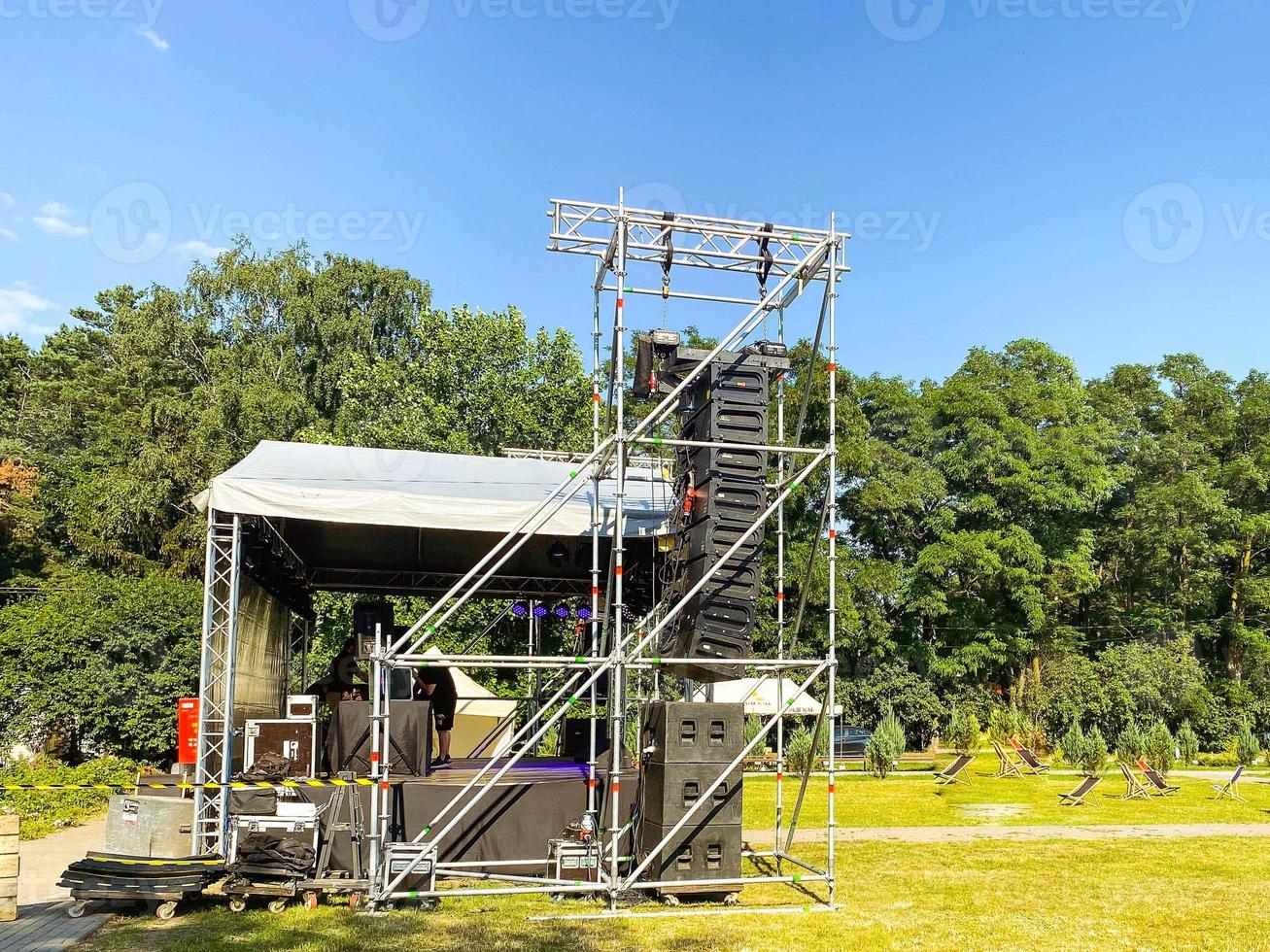 straat concert. de stadium is reeks Rechtsaf in de park. gemaakt van metaal structuren, tegen de backdrop van groen bomen. luid luidsprekers Aan stadium foto