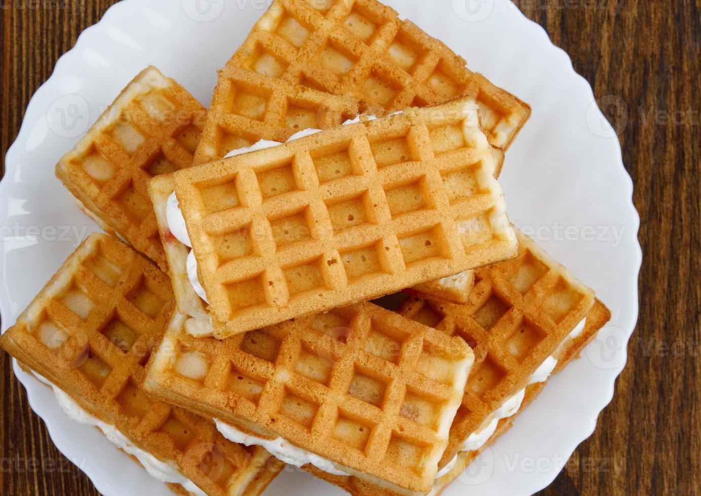 een stapel van rossig weens wafels liggen Aan een wit bord Aan een houten achtergrond. foto