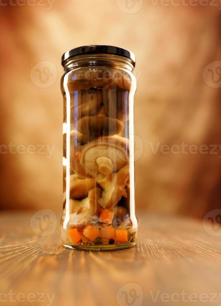 een pot van mooi gepekeld champignons Aan een houten tafel foto
