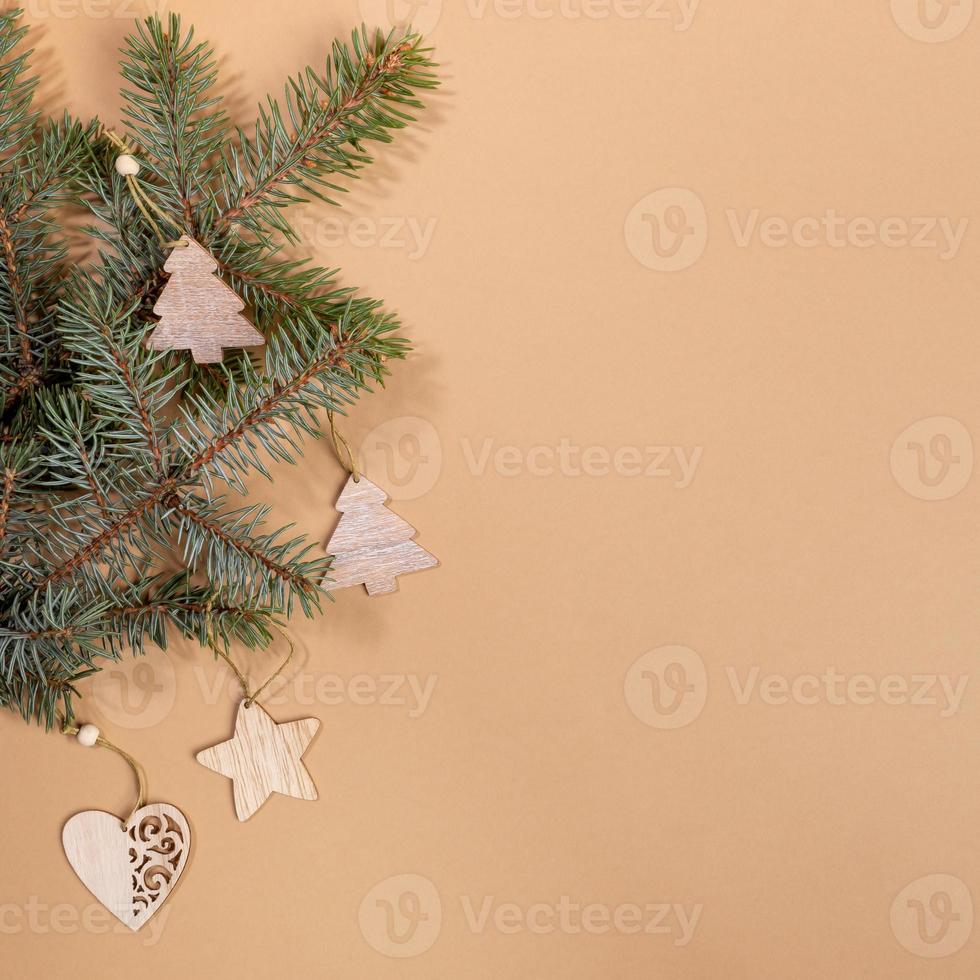 Kerstmis feestelijk lay-out met groen Spar boom takken en feestelijk houten ambacht decoraties Aan beige met kopiëren ruimte. foto