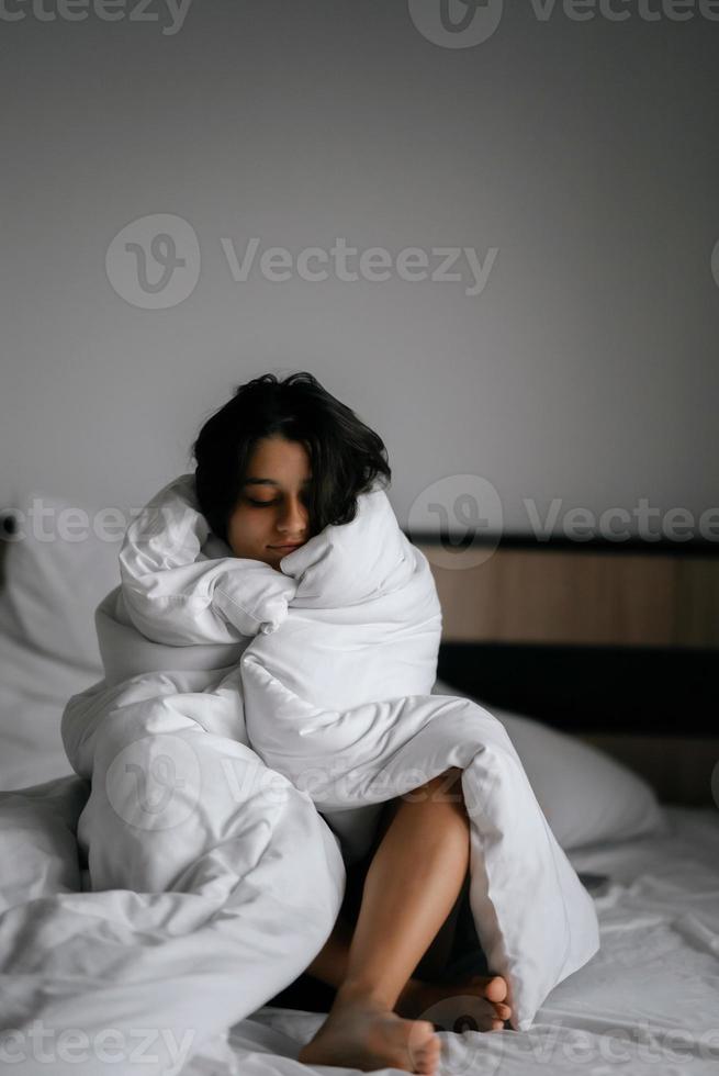 lui vrouw verpakt in zacht deken zittend in knus bed foto