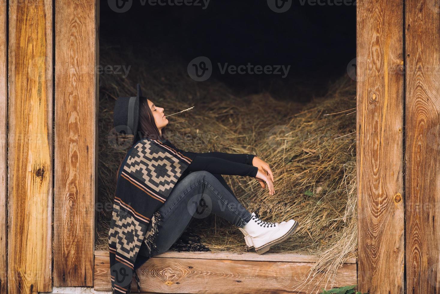 jong brunette vrouw zittend Bij de schuur. land stijl. foto