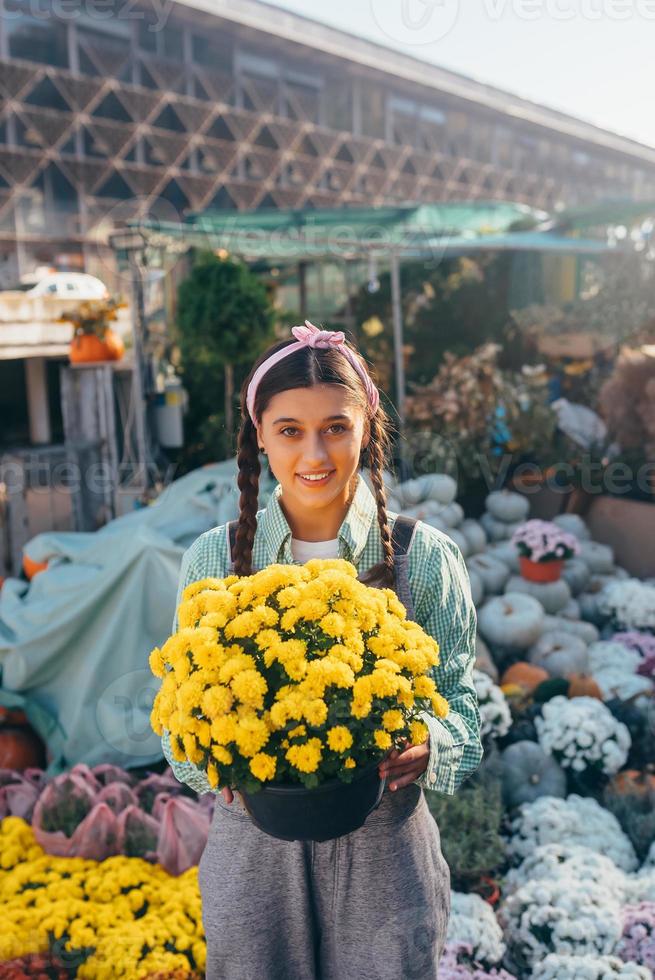 vrouw Holding decoratief bloem in bloem pot Aan de markt. foto