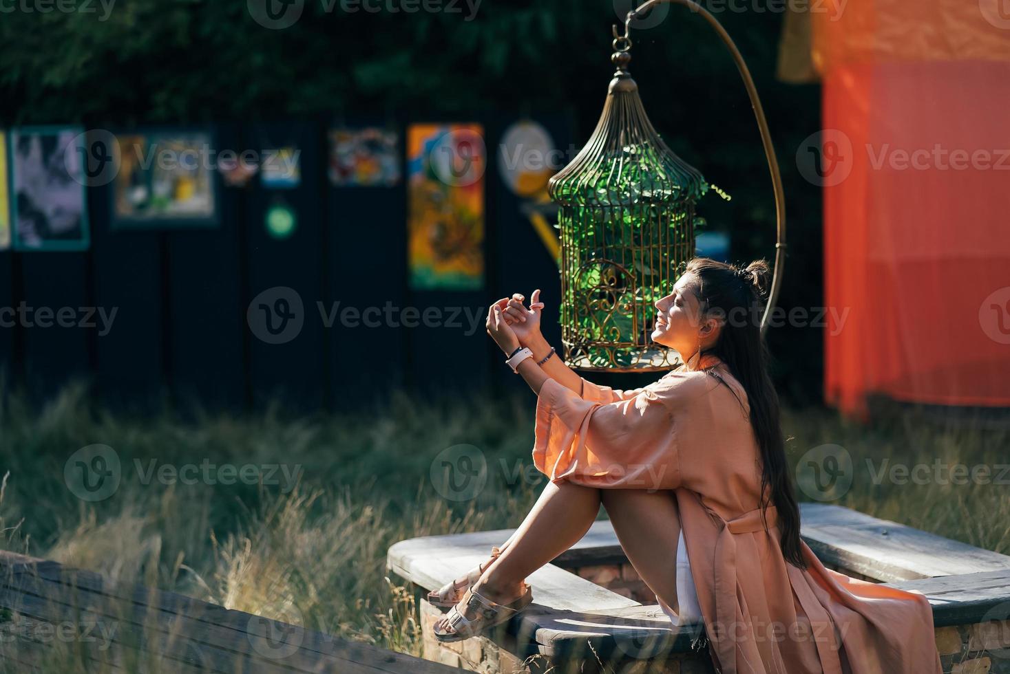 brunette vrouw zittend Aan bank en genieten van de zonsondergang foto