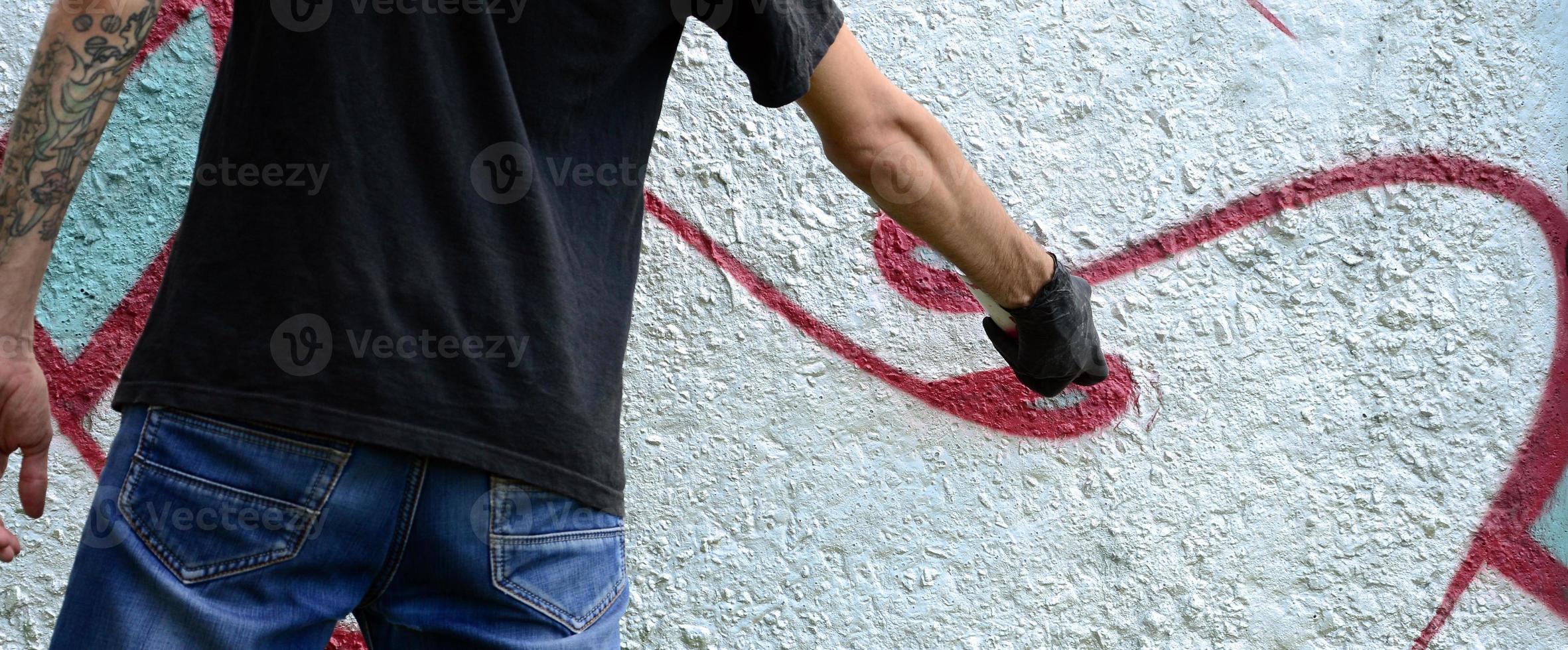 een jong hooligan verven graffiti Aan een beton muur. onwettig vandalisme concept. straat kunst foto