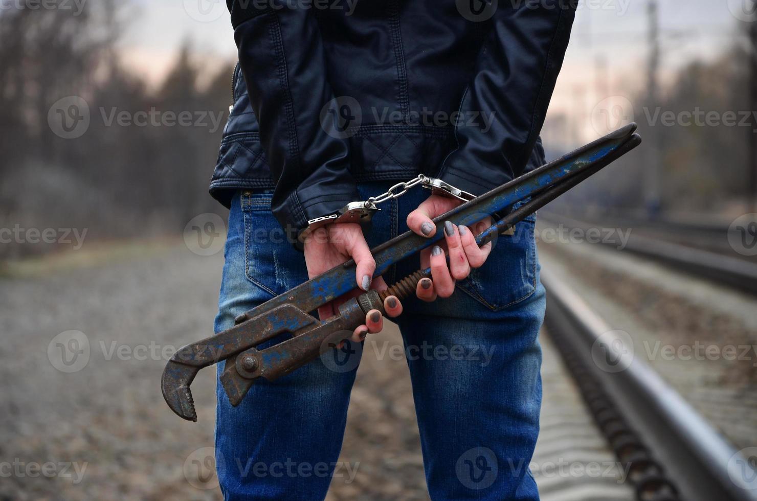 de meisje in handboeien met de pijp moersleutel Aan de spoorweg bijhouden foto