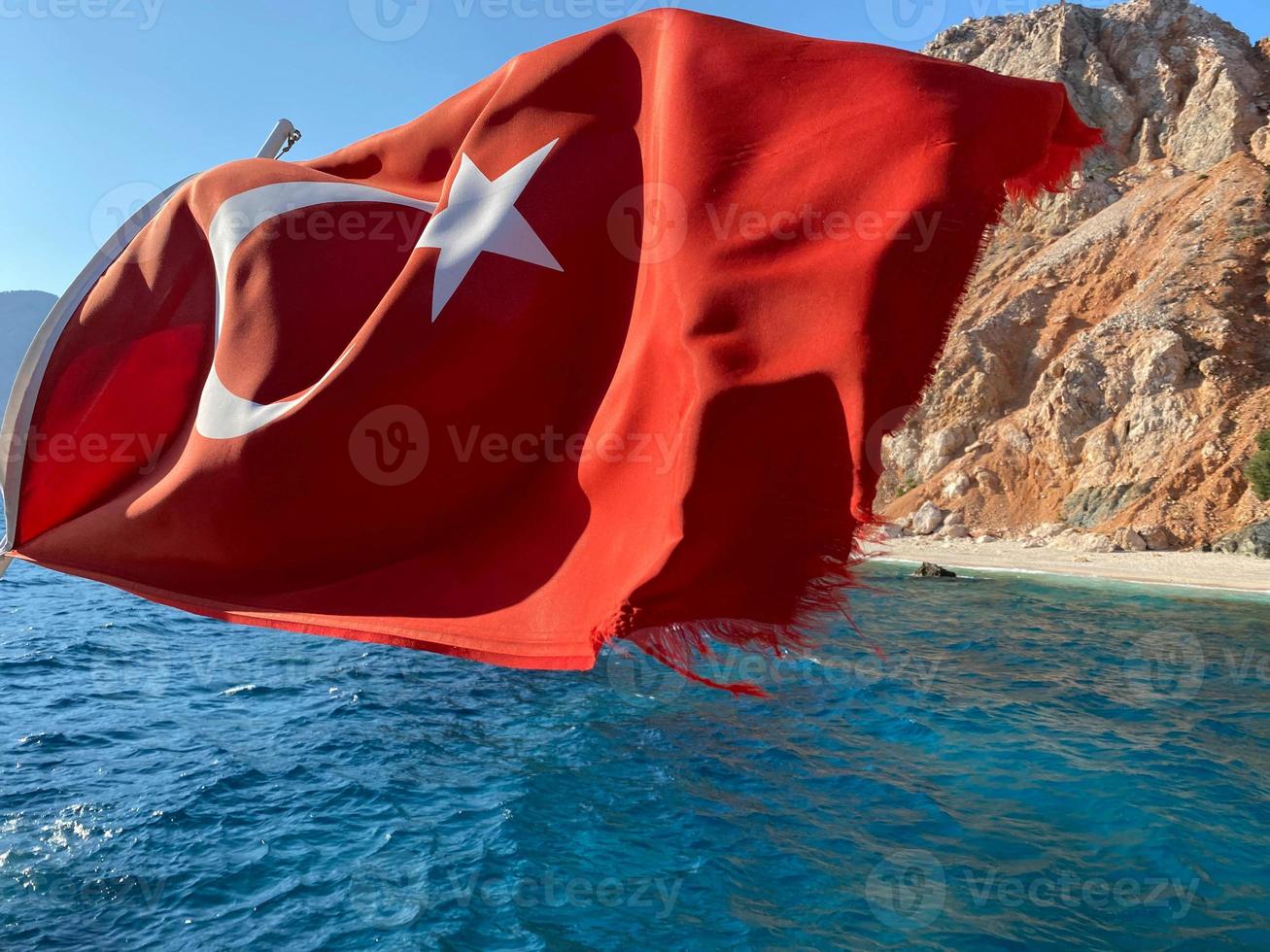 Turks vlag Aan de achtergrond van de zee en bergen in zonnig weer foto