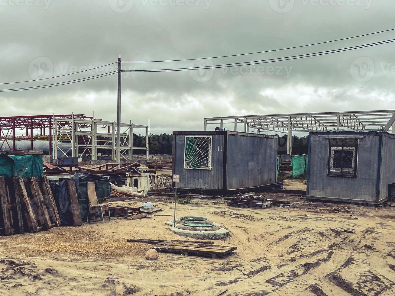 bouw plaats van een industrieel complex. klein huizen voor Bouwers met ramen Bij de plaats van de bouw van de fundament. aarde Aan de straat, gebouw materiaal leugens foto