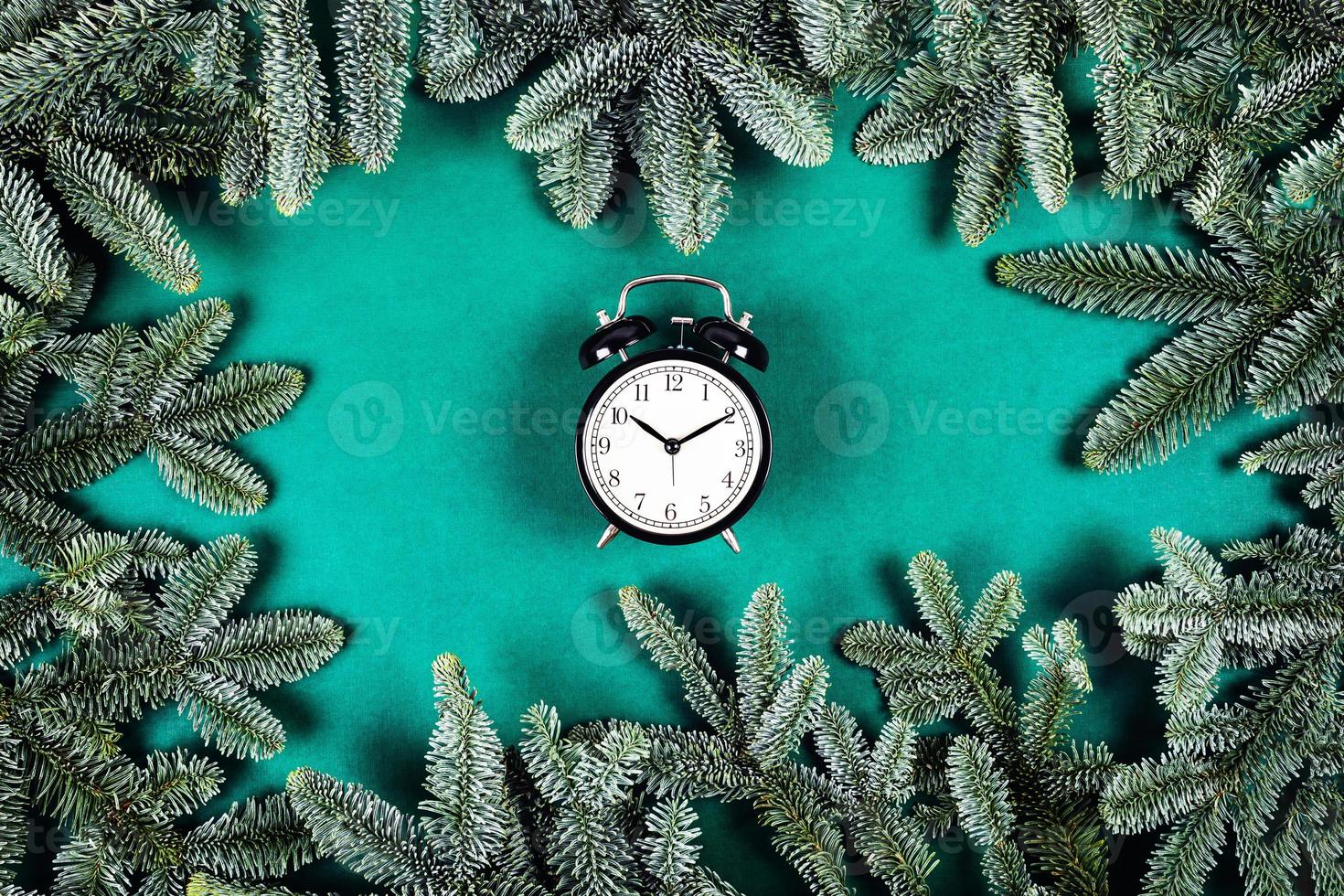 zwart klok Aan groen achtergrond met Kerstmis takken. foto