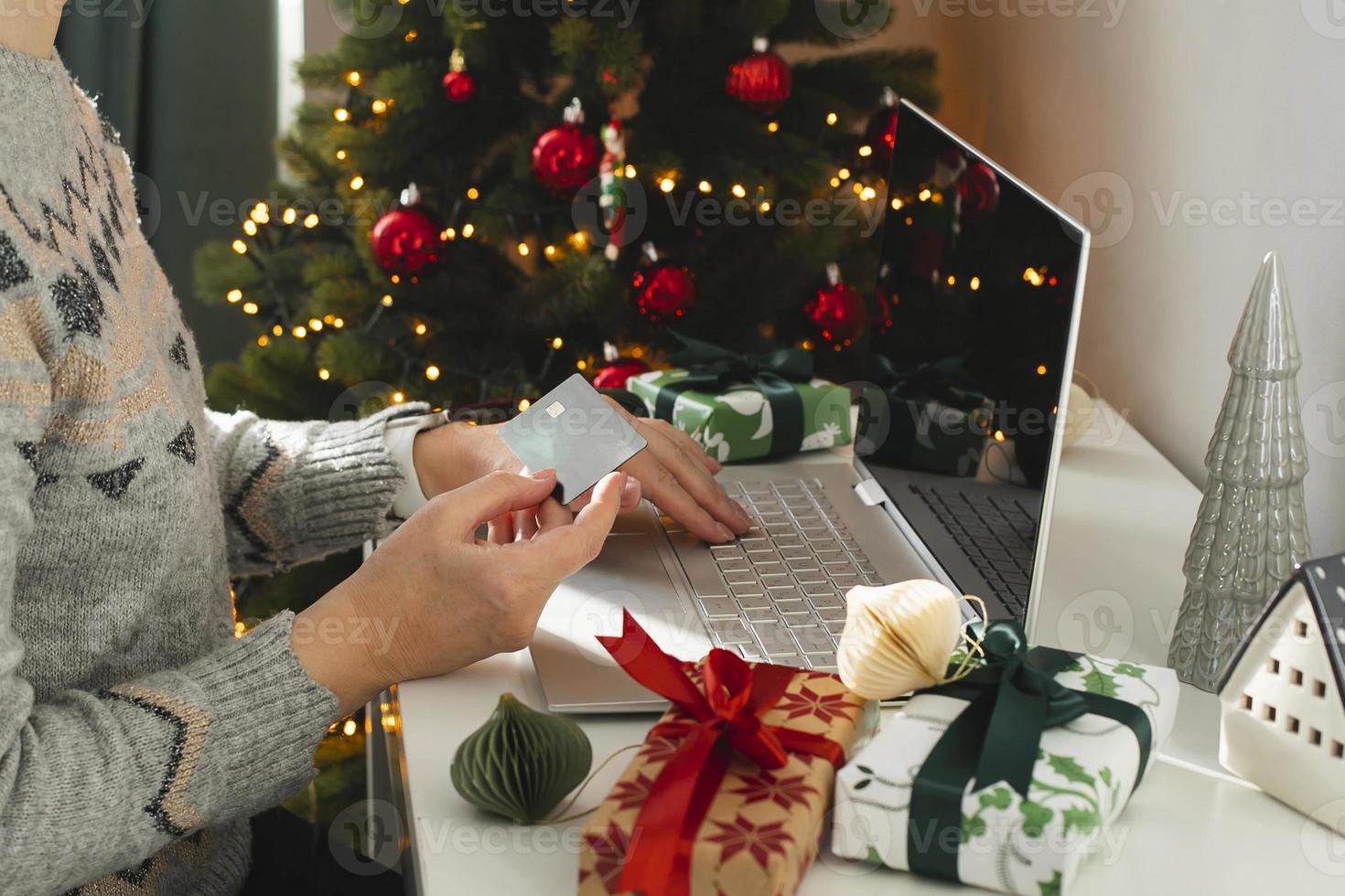 vrouw hand- Holding kaart en gebruik makend van laptop voor Kerstmis online winkelen. vakantie online boodschappen doen concept. winter vakantie verkoop, zwart vrijdag foto