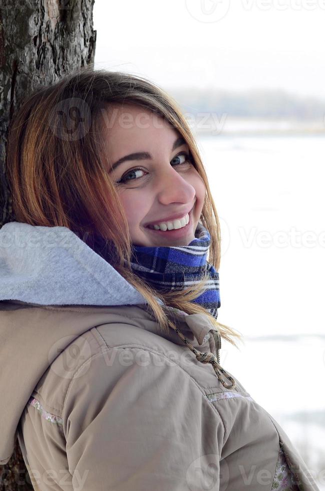 een jong en glimlachen Kaukasisch meisje looks in de omgeving van de horizon lijn tussen de lucht en de bevroren meer in winter tijd foto