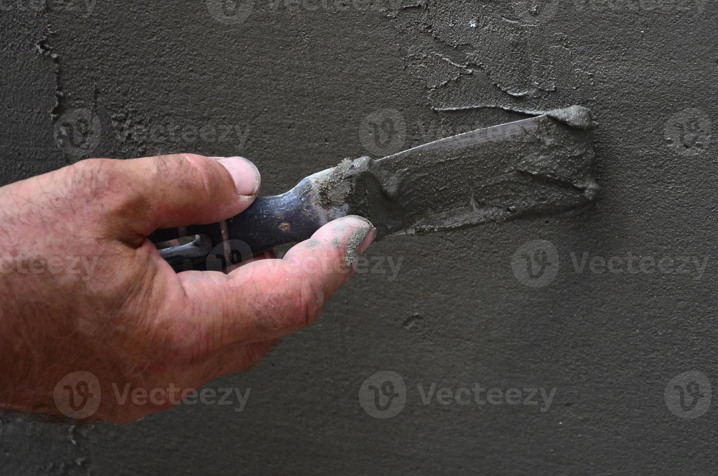 handen van een oud handleiding arbeider met muur bepleistering gereedschap renoveren huis. stukadoor renoveren buitenshuis muren en hoeken met spatel en gips. muur isolatie. bouw afwerking werken foto