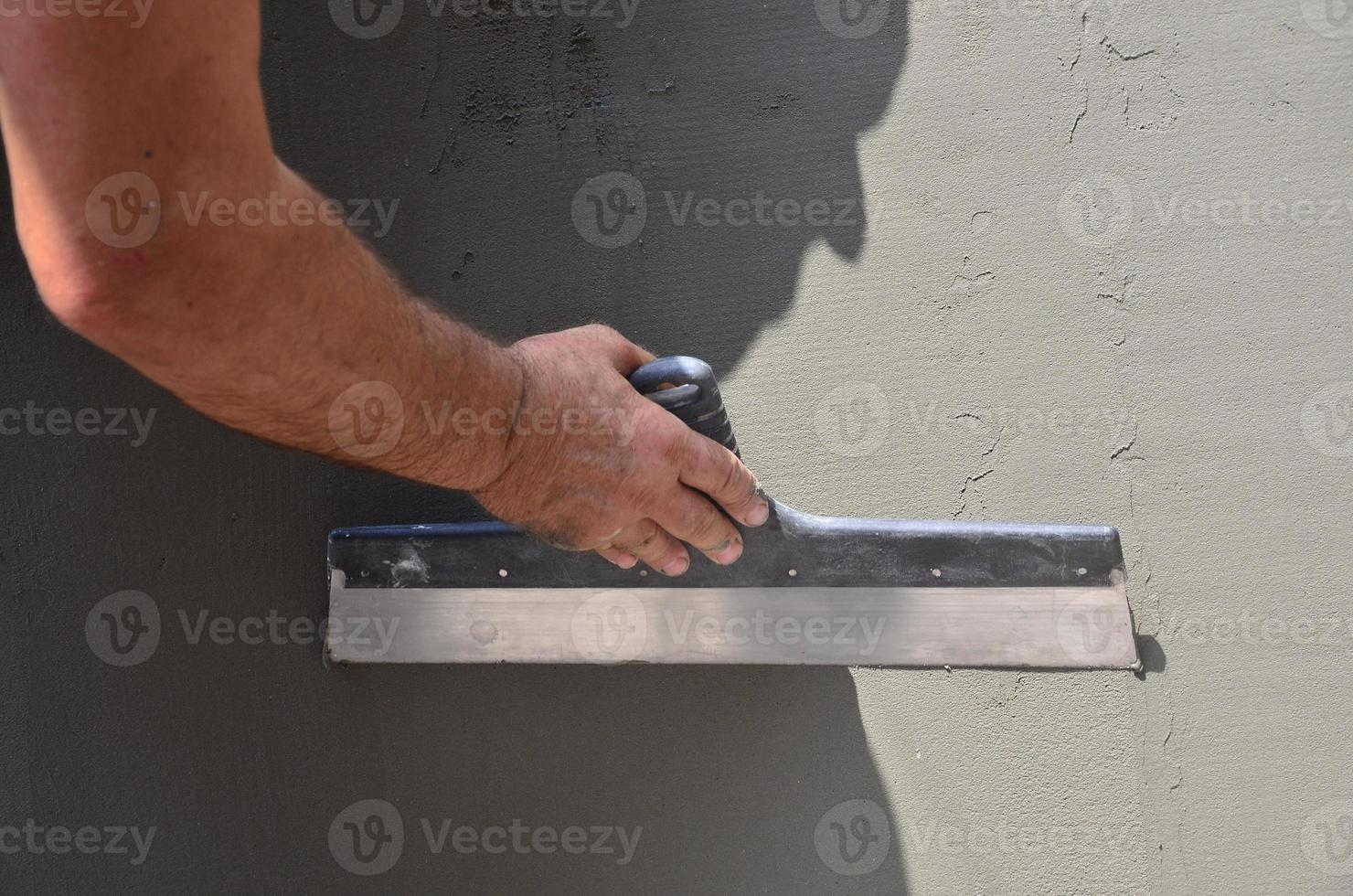 handen van een oud handleiding arbeider met muur bepleistering gereedschap renoveren huis. stukadoor renoveren buitenshuis muren en hoeken met spatel en gips. muur isolatie. bouw afwerking werken foto