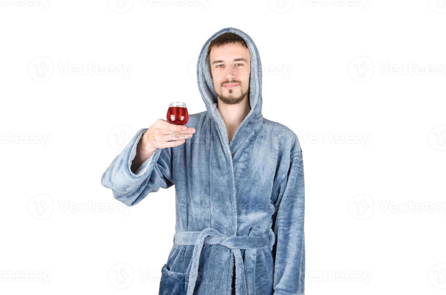 portret van jong Kaukasisch gebaard Mens in blauw badjas verhoogt glas van rood wijn geïsoleerd Aan wit achtergrond foto