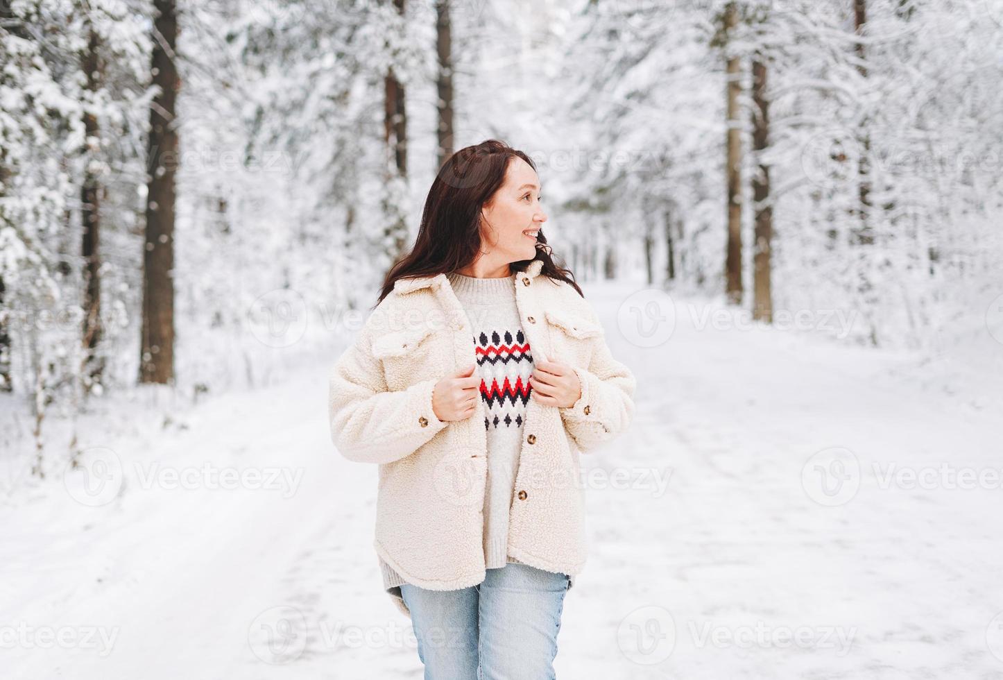 glimlachen volwassen vrouw met donker haar- in winter kleren in besneeuwd winter Woud foto