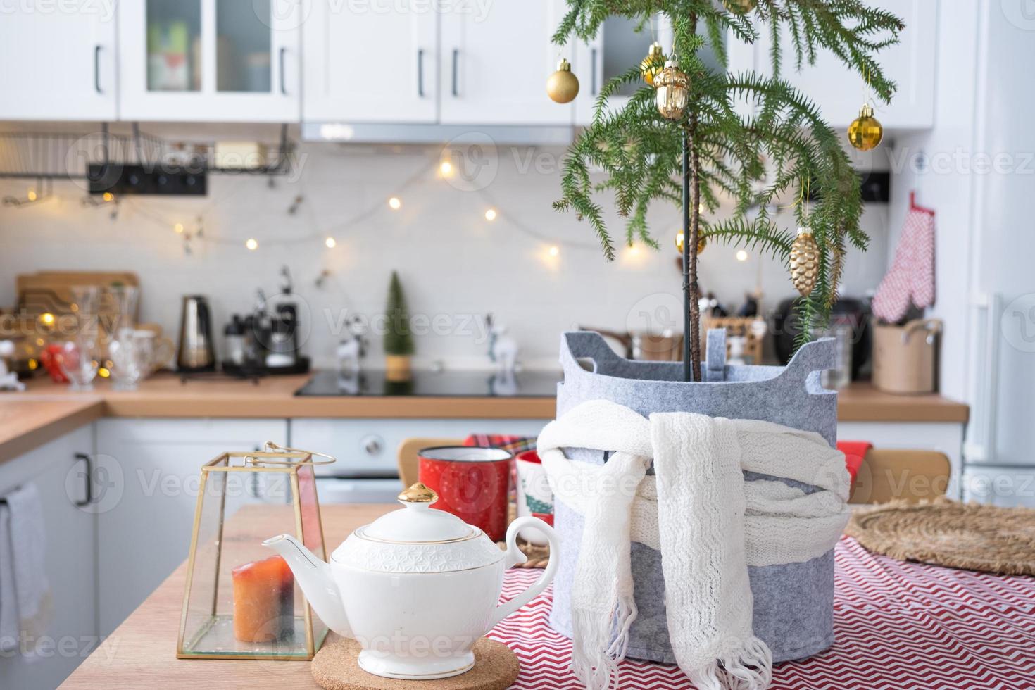 feestelijk Kerstmis decor in wit keuken, feestelijk ontbijt, wit scandi interieur. araucaria net zo een Kerstmis boom is versierd en verpakt in een sjaal en voelde plantenbakken. nieuw jaar, stemming, knus huis foto