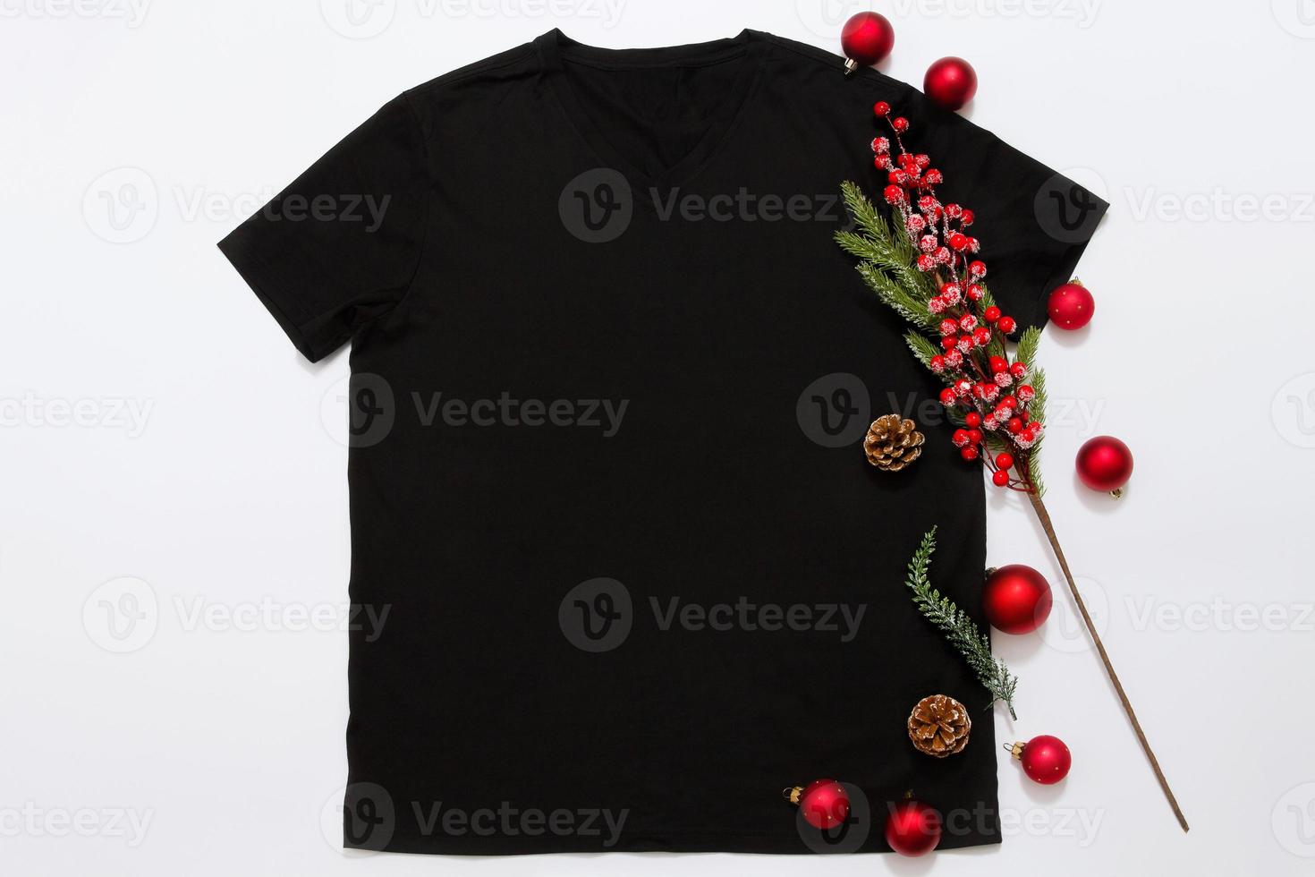 dichtbij omhoog zwart blanco sjabloon t overhemd met kopiëren ruimte en Kerstmis vakantie concept. top visie mockup t-shirt en rood vakantie decoraties Aan wit achtergrond. gelukkig nieuw jaar accessoires. Kerstmis kleding foto