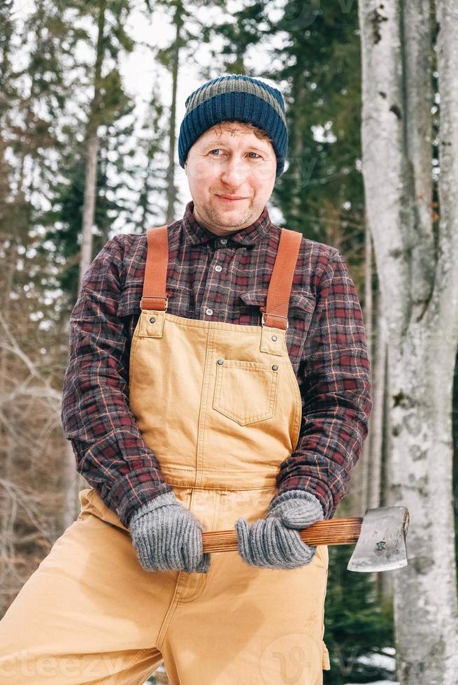 man houthakker met een bijl in zijn handen op een achtergrond van bos en bomen foto