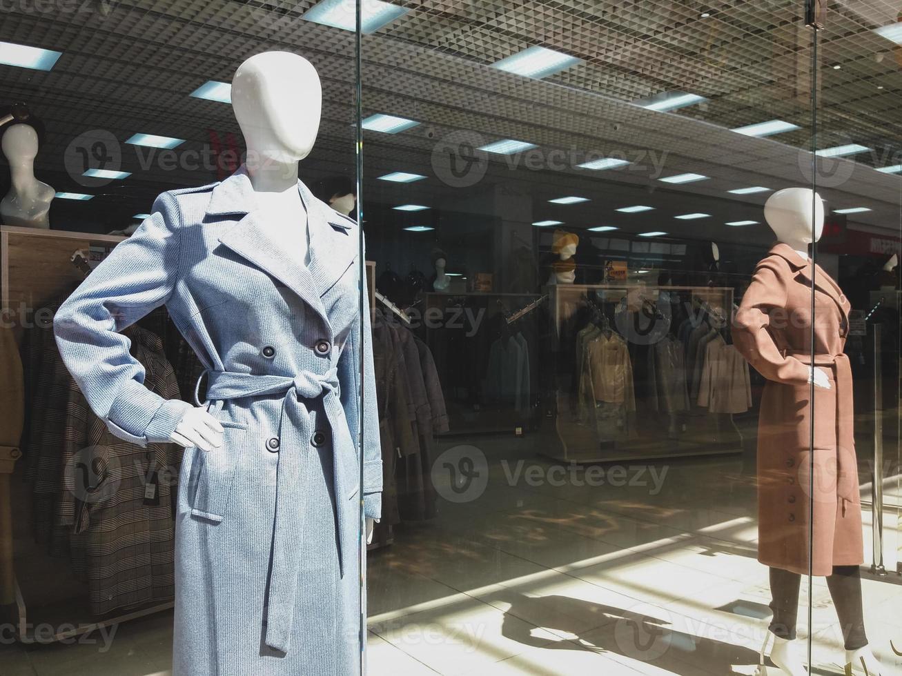 herfst verzameling van jassen in kleding op te slaan, vrouw etalagepoppen in winkel venster foto