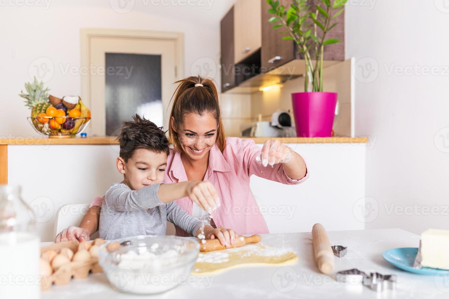 gelukkig liefhebbend familie zijn voorbereidingen treffen bakkerij samen. moeder en kind zoon jongen zijn Koken koekjes en hebben pret in de keuken. eigengemaakt voedsel en weinig helper. foto